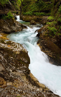 Wood walkway over turquoise waterfalls and rapids on Radovna river Vintgar Gorge forest with sedimentary limestone rock layers S