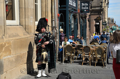 Scottish bagpiper in tartan kilt playing the bagpipes on the Royal Mile in Edinburgh for tourists in Scotland