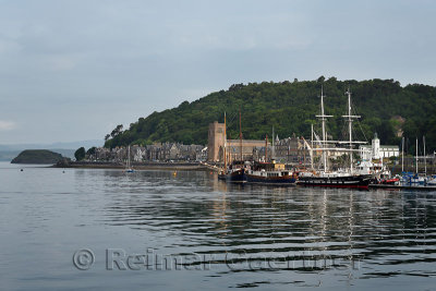 Sailing ships moored in Oban Harbour with St Columbas Cathedral on Oban Bay in the morning Scotland UK