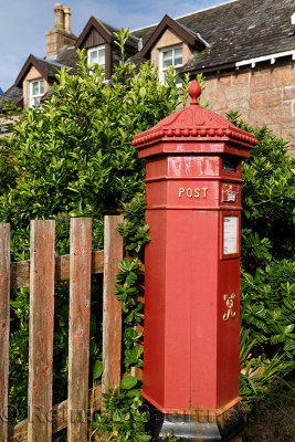 Red Royal Mail Post Office box with evergreen Hebe bush at Baile Mor village on Isle of Iona Inner Hebrides Scotland UK