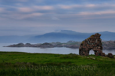 Granite stone ruins of the Bishop's House next to Iona Abbey at dusk on Isle of Iona with view over Sound of Iona to Isle of Mul
