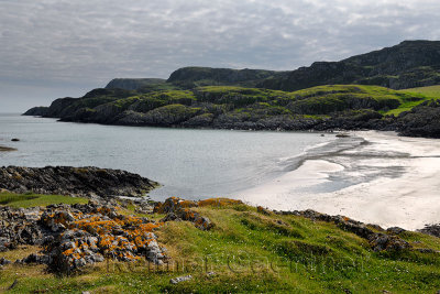 Lichen covered rocks at Sandeels Bay above sandy beach on Isle of Iona Inner Hebrides Scotland UK