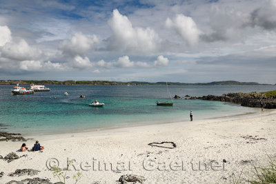 White sand beach of Martyr's Bay on Isle of Iona looking at Isle of Mull and boats in Sound of Iona Inner Hebrides Scotland UK