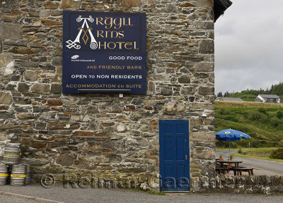 Stone wall of Argyll Arms Hotel with blue sign open to non residents and beer kegs in Bunessan on Isle of Mull Scotland UK