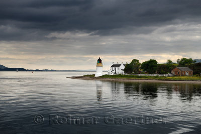 Corran Lighthouse and Lodge under dark clouds in Ardgour on Isle of Mull from the Ferry on Loch Linnhe Scotland UK