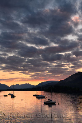 Red Sunset with clouds on Loch Leven with moored sailboats at Glencoe Boat Club Scottish Highlands Scotland UK
