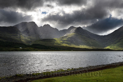 Sun rays on Bla Bheinn mountains outlier of the Black Cuillin with dark clouds and Loch Slapin from Torrin Isle of Skye Scotland
