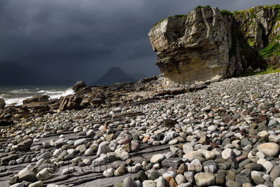 Smooth boulders of Elgol beach at Port na Cullaidh with Red Cuillin Mountains under clouds on Loch Scavaig Isle of Skye Scotland