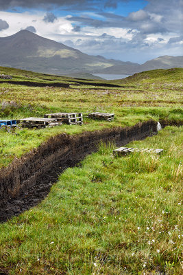 Trench cut into deep Peat of wetland moors near Drinan on Isle of Skye Scotland with Loch Slap and Beinn Na Caillich mountain pe
