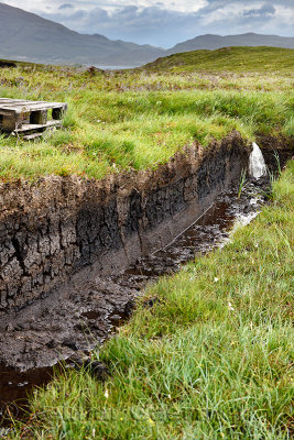 Trench cut into deep Peat of wetland moors near Drinan on Isle of Skye Scotland with Loch Slap to drain water for harvest