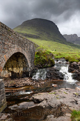 Stone bridge of Bealach na Ba road mountain pass over Russel Burn river and Sgurr A Chaorachain peak in Scottish Highlands Scotl