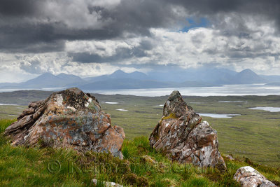 Lichen encrusted rocks overlooking the Inner Sound to Scalpay Island and the Cuillin Hills mountains Isle of Skye Scottish Highl
