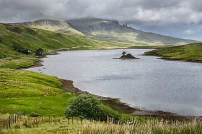 Dappled sun on The Storr mountain peaks with The Old Man of Storr in clouds over Loch Fada Isle of Skye Scottish Highlands Inner