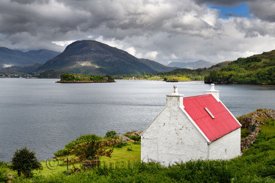 White stone house with red roof on Loch Shieldaig with Eilean an Inbhire Bhain Island and Ben Shieldaig Peak Scottish Highlands 