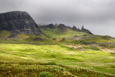 Sun on green pasture before The Old Man of Storr in clouds at The Storr cliff Trotternish peninsula Isle of Skye Scottish Highla