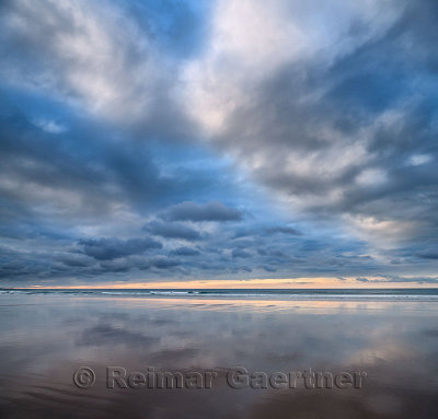 Clouds at sunset reflected in wet sand of wide Inverboyndie Beach with Atlantic Ocean surf at Boyndie Bay Aberdeenshire Scotland
