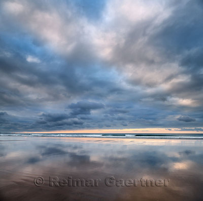 Clouds at sunset reflected in wet sand of wide Inverboyndie Beach with surf at Boyndie Bay Aberdeenshire Scotland UK