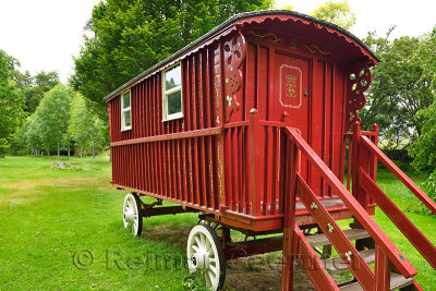 Red painted renovated Gypsy Traveler Caravan parked at the green Cawdor Castle grounds in the rain Nairn Scotland UK