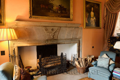 Drawing Room at Cawdor Castle Scotland with plush chairs around fireplace staghead buckle emblem and framed family paintings 