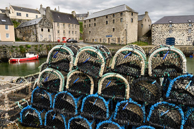 Lobster traps on stone dock of Old Harbourside Portsoy with stone Portsoy Marble warehouse Aberdeenshire Scotland UK