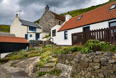 Rock garden and stone houses built into the hillside of coastal fishing village of Crovie Banff Aberdeenshire Scotland UK