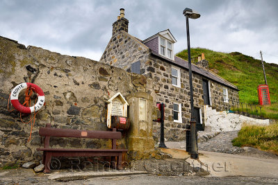 Red Telephone booth and Crovie Pier lifebuoy with stone house in Crovie coastal fishing village Banff Aberdeenshire Scotland UK