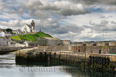 Stone piers at MacDuff Harbour shipyards with Macduff Parish Church on hilltop with clouds Macduff Aberdeenshire Scotland UK