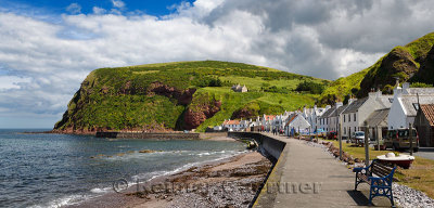 Row of white houses of Pennan coastal fishing village on North Sea in Aberdeenshire Scotland UK with Black Hill sea cliff