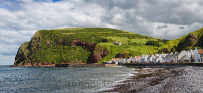 Stone beach and row of white houses of Pennan coastal fishing village on North Sea in Aberdeenshire Scotland UK with Black Hill 