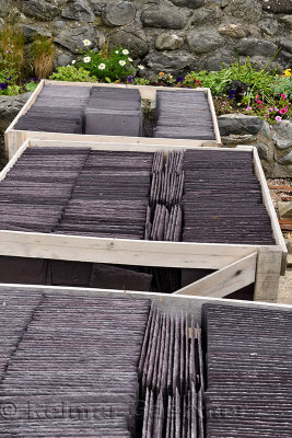 Boxes of new slate roof tiles at a rock wall flower garden in Crovie Banff Aberdeenshire Scotland UK