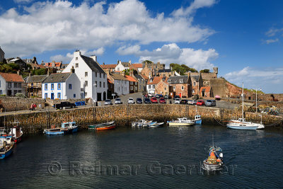 Fisherman on boat leaving Crail Harbour with stone piers and Crail House turret overlooking the North Sea Scotland UK