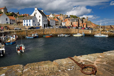 Fisherman on boat returning to Crail Harbour with stone piers and iron morring ring on the North Sea Scotland UK