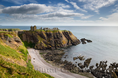 Pebble beach at Old Hall Bay North Sea with Donnottar Castle Medieval clifftop fortress ruins near Stonehaven Scotland UK