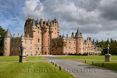 Front lawn of Glamis Castle childhood home of Queen Mother with statues of King James I and Charles I with sun and clouds Scotla