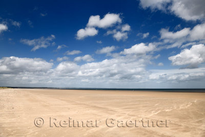 High wind on wide long St Andrews West Sands beach with blue sky and white clouds St Andrews Fife Scotland UK