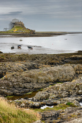 Lindisfarne Castle with scaffolding from Steel End of Holy Island with fishing boats at low tide Berwick-upon-Tweed England UK