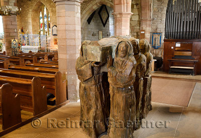 Wood sculpture of monks carrying dead monk in coffin in the nave of The Parish Church of Saint Mary the Virgin on Holy Island of