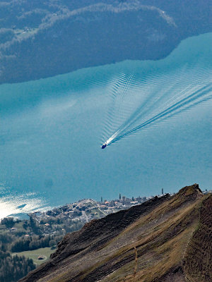 Looking down from the peak of Brienzer Rothorn to the Lake of Brienz where we can see a passenger boat of the public transport