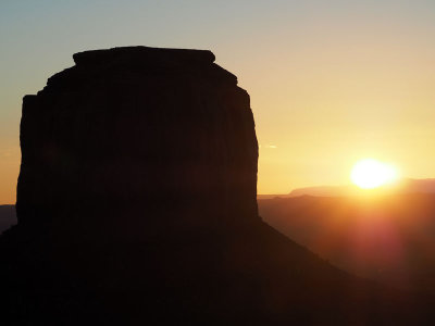 Sun almost clears the horizon next to Merrick butte in Monument Valley