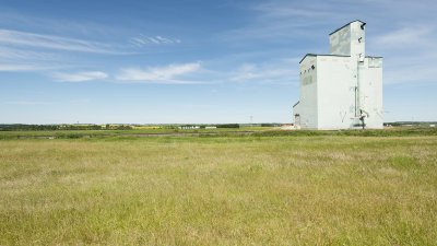 A grain elevator on a blue sky prairie landscape.