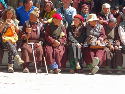 A crowd at a mask dance presentation; maybe one person is sleeping?