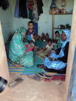 Women and children in a small, one room house