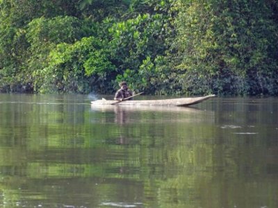 Everyone along the river has a boat; notice the fire on its stern to ward off mosquitoes.