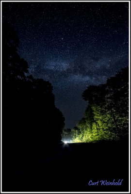 A car rounds a turn on Rt 44 as the Milky way hovers overhead. 