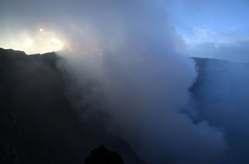 Smoke rising from the crater of Nyiragongo mostly obscuring the lava lake