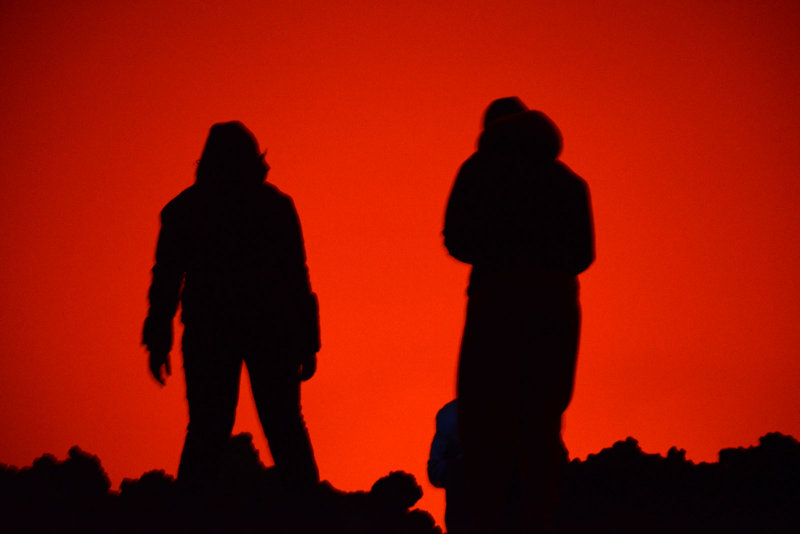 A pair of visitors silhouetted against the fiery glow of Nyiragongo's molten interior