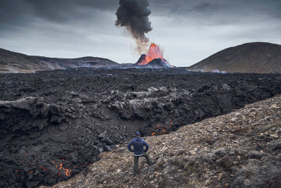 Despite this being an otherworldly experience, it begins, like many adventures, in a car park. Ever since the Gerlingadalur eruption began on March 19, 2021, Icelanders—and now vaccinated international visitors such as myself —have made pilgrimages to see the lava spew, bubble, and flow across this stretch of the Reykjanes Peninsula in southwestern-most Iceland. What’s astonishing is that this once-in-800-years display of nature’s force is only a 45-minute drive south of Reykjavík. It’s even closer to Keflavík Airport, the largest airport in the country—a mere 20 minutes by car. Imagine that: an active volcano one would deem “accessible.” You could land in Iceland in the morning from the United States (there are flights from Boston, JFK-NYC, and Washington, D.C., as of May), await your negative COVID test results at a nearby hotel, and once cleared, see the volcano erupt in the same day.