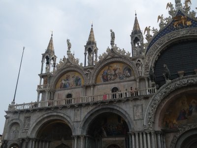 People on the balcony of St Mark's with more overly ornate decorations above them.