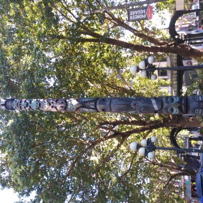 Tlingit totem pole flanked by turn-of-the-century street lamps in front of 1909 cast iron & glass  pergola in Pioneer Square   