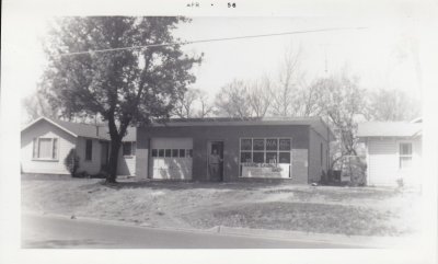 April 1956, MA Harris in front of his cabinet shop on May Ave between Bill and Jackie Harris's house on the South (left) and MA and Rudel's house on the right. [house];